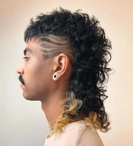 Dolga moška mullet frizura z valovitim undercut dizajnom ob sencih.
